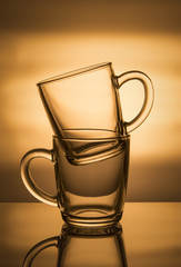 Two glass cups on an orange background.