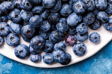 Fresh blueberries on a white plate and blue background. Concept  Healthy Food. Diet Nutrition .Top View. Flat Lay.selective focus.