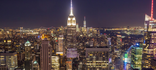 View of Manhattan skyline at night. The entire city is awash in light with the Empire State Building in center of frame.