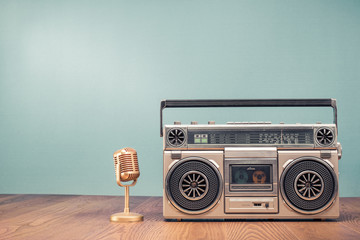 Retro outdated portable stereo boombox radio receiver with cassette recorder from circa 80s and golden mic front mint green wall background. Recording music concept. Vintage old style filtered photo