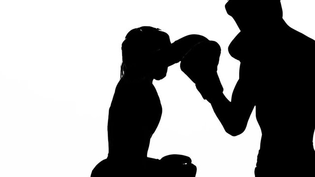 Girl is kicking the guy they are sparring for kickboxing . Silhouette. White background