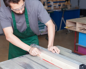 Carpenter working with Industrial tool in wood factory, circular blade with a wood board
