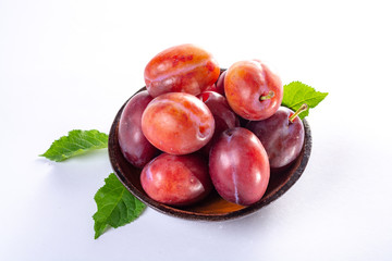 Fototapeta na wymiar Group of ripe oval Victoria plums from England on white background with leaves
