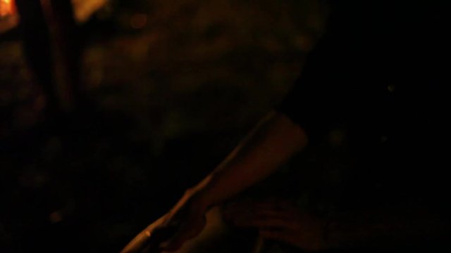 Man playing djembe in front of a fire at night