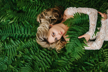 A beautiful girl lies in a fern.