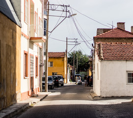 Fototapeta premium a nice view from a narrow street at a village - some people and cars is there