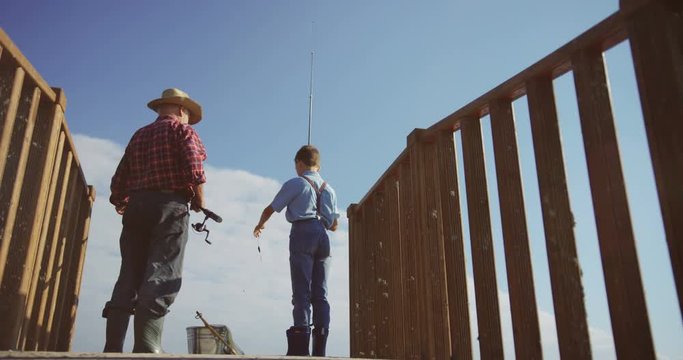 View from below on the pld fisherman with a little boy fishing from a wooden bridge. Outdoors.