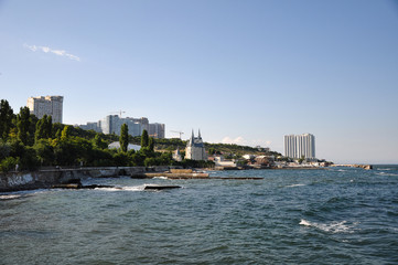 Embankment of the Black Sea. Small waves and a beautiful panorama of the sea. Classical and modern buildings. The slopes are covered with green trees. Light wind and good weather. 