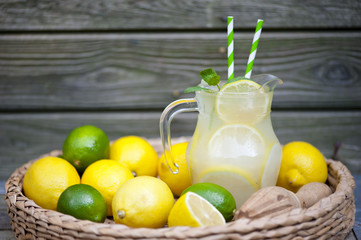 Preparation of the lemonade drink. Lemonade in the jug and lemons with mint on the table outdoor