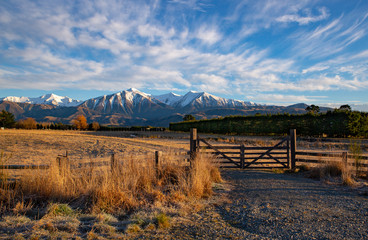 Under the snow capped mountains and beautiful winter scenery, a gate that leads in to the farm is closed