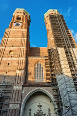 Naklejka premium Munich, Germany June 09, 2018: The Frauenkirche (also known as: Dom zu Unserer Lieben Frau, Cathedral of Our Dear Lady, Münchner Dom, Munich Cathedral) towers over a downtown street.