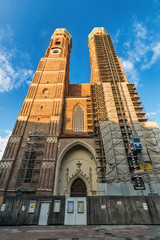 Naklejka premium Munich, Germany June 09, 2018: The Frauenkirche (also known as: Dom zu Unserer Lieben Frau, Cathedral of Our Dear Lady, Münchner Dom, Munich Cathedral) towers over a downtown street.