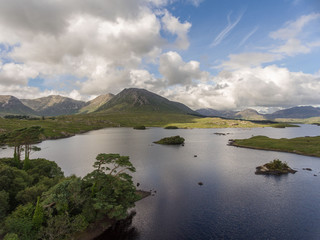 Aerial birds eye scenic view from Connemara National Park in County Galway, Ireland. Beautiful Irish rural nature countryside landscape with mountains in the distance.