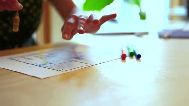Woman using a pendulum over a house plan