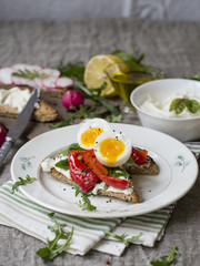 Toast with egg, red pepper, cheese and rucola on a white plate. Breakfast. Background made of linen cloth. Close up