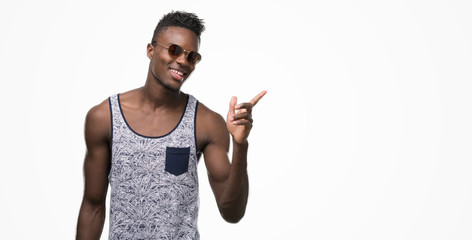 Young african american man wearing sunglasses very happy pointing with hand and finger to the side