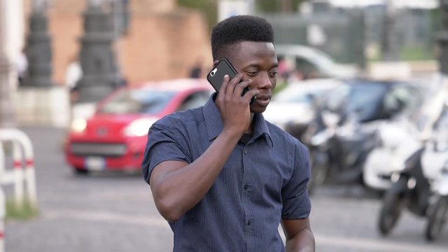 handsome black african man in the street, talking by phone