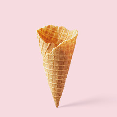Wafer ice cream cone on a light pink background. Minimalistic concept.