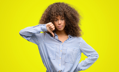 African american woman wearing a stripes shirt with angry face, negative sign showing dislike with...