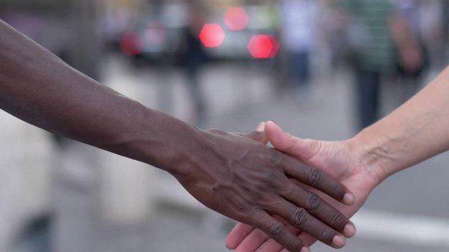 handshake between hand of black man and white woman - outdoor