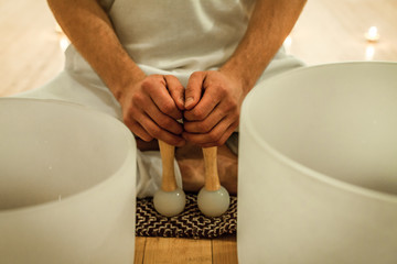 Man his holding his crystal bowl drum sticks while sitting in indian