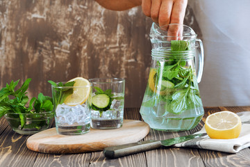 Detox water with lemon, cucumber and mint on rustic wooden background.Man preparation detox.