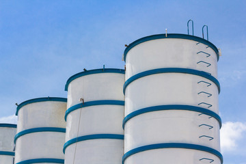 white and blue steel silos against blue sky use for concrete mix for construction site.
