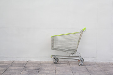 green steel shopping cart on concrete floor background.