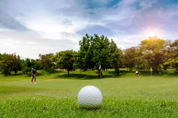 Golf ball on the golf course with the blurred of golfers, Sport and recreation playground for golf club on holiday , vacation time concept