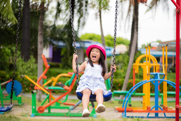 Cute little girl having fun with swing in the park.Children playground.