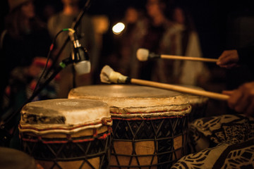 Naklejka premium Drumsticks on djembe, recorded by a microphone during a live performance in front of a crowd