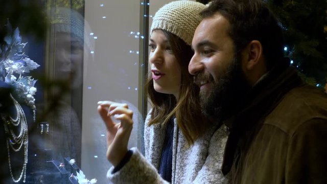 Happy couple looking at jewelry window in the street. Christmas- slow motion