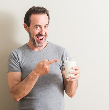 Senior Man Drinking A Glass Of Milk Very Happy Pointing With Hand And Finger