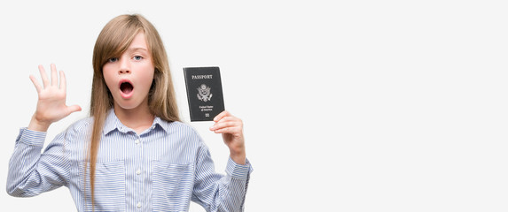 Young blonde toddler holding american passport very happy and excited, winner expression celebrating victory screaming with big smile and raised hands