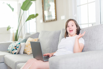 Down syndrome woman at home using computer laptop very happy and excited, winner expression celebrating victory screaming with big smile and raised hands