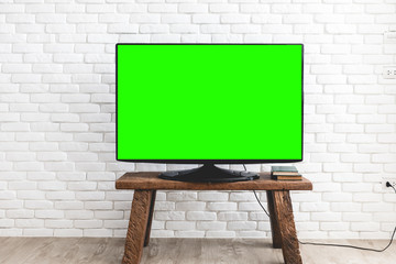 Empty green flat TV screen on wood stand.