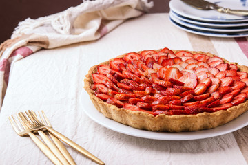Fresh homemade strawberry tart with custard on rustic tablecloth. Delicious holiday berries summer dessert