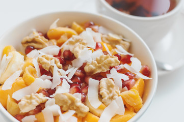 Healthy fruit mix: mango, banana, tangerine, pomegranate seeds, coconut flakes and wulnut served with a cup of hibiscus tea