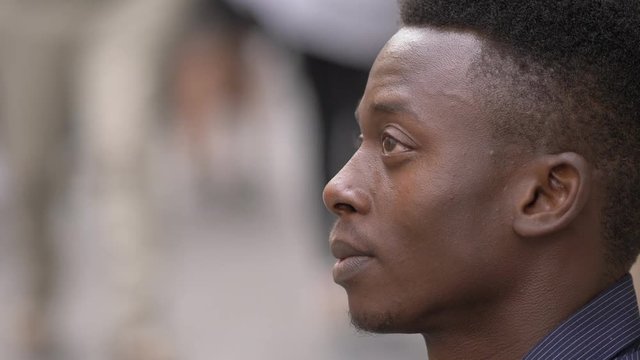 Pensive depressed young african man in the street- profile