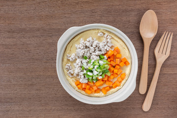 homemade style steamed egg with pork and vegetable in a ceramic bowl on wooden table, top view. healthy food concept.