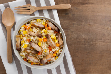 top view of fried rice with pork belly in a ceramic bowl on old wooden table. asian homemade style food concept.