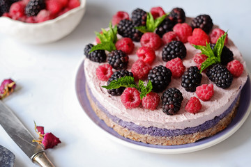 Raw vegan cake with raspberries and bluberries on white table