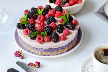 Raw vegan cake with raspberries and bluberries on white table