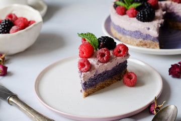 Raw vegan cake with raspberries and bluberries on white table