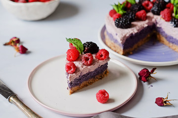 Raw vegan cake with raspberries and bluberries on white table