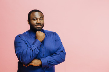 Portrait of a confident man in casual blue shirt with arms crossed, isolated on pink background