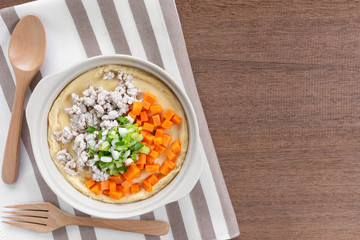 homemade style steamed egg with pork and vegetable in a ceramic bowl on wooden table. healthy food concept.