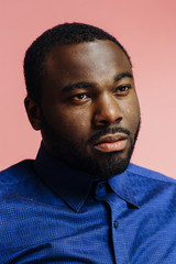 Fototapeta premium Portrait of a serious man in blue shirt looking off camera, isolated on pink background