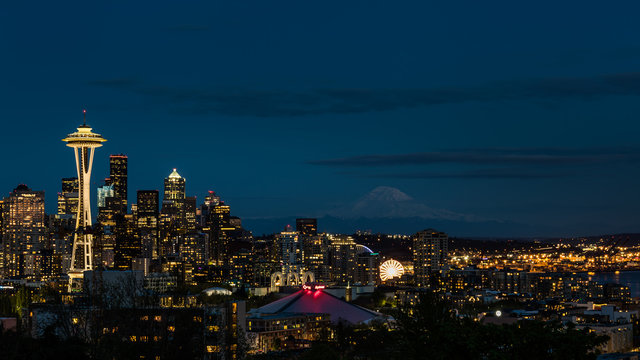 Seattle skyline lit up at night with Mount Rainier