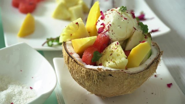 Making a fruit mix icecream in a coconut bowl with flower topping